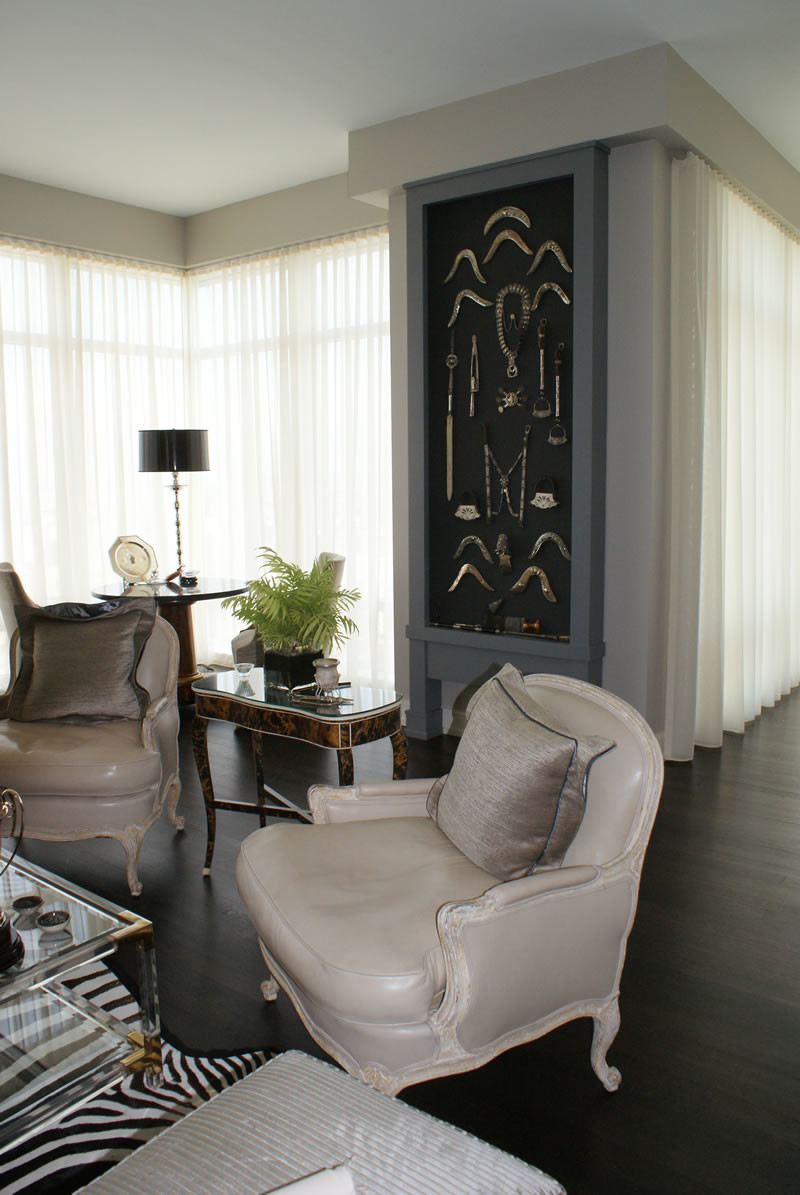Pair of soft taupe leather covered antique chairs on dark wood floors showcasing floor-to-ceiling sheer sheathed windows.